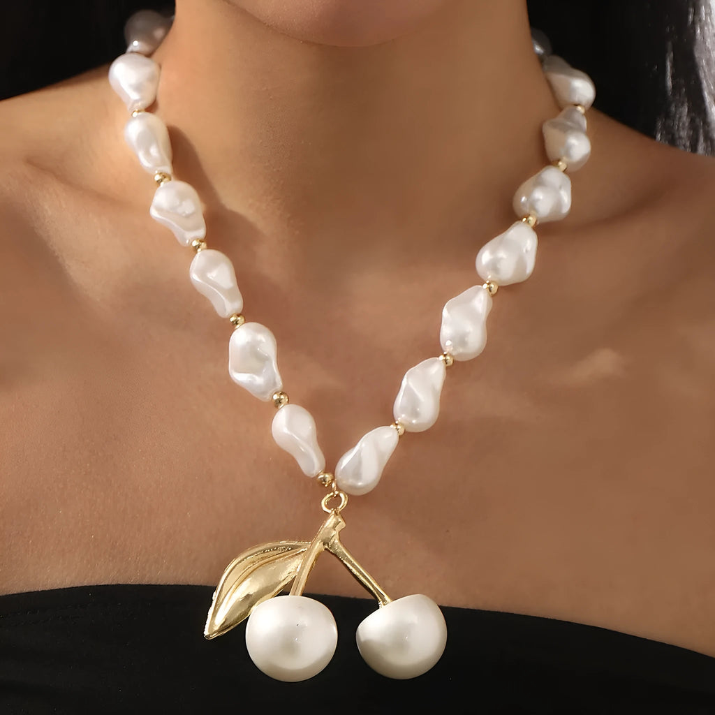 Gold-tone irregular cherry fruit pendant on an adjustable string of white imitation pearls necklace.