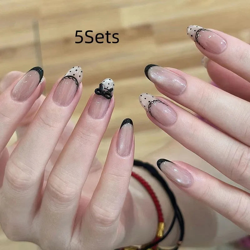 Set of medium-length coffin-shaped false nails with French manicure glitter tips and rhinestone decorations.