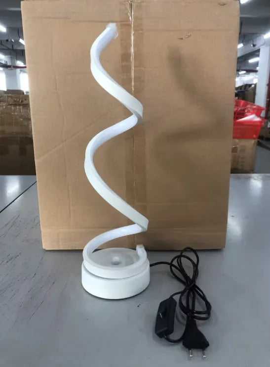 Modern LED table lamp with gold metal base and curved acrylic shade on a desk