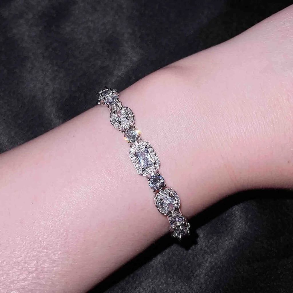 Women's geometric silver bracelet with inlaid zircon stones on a wrist, showing adjustable chain.
