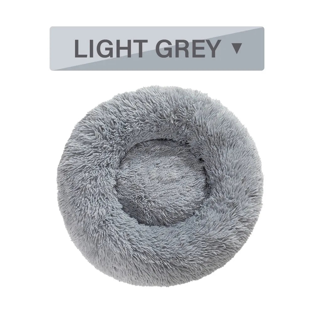 Fluffy grey donut-shaped dog bed with high plush sides on a wooden floor.