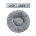 Fluffy grey donut-shaped dog bed with high plush sides on a wooden floor.