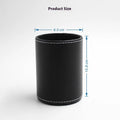 A small, round black leather pen holder standing on a wooden desk.