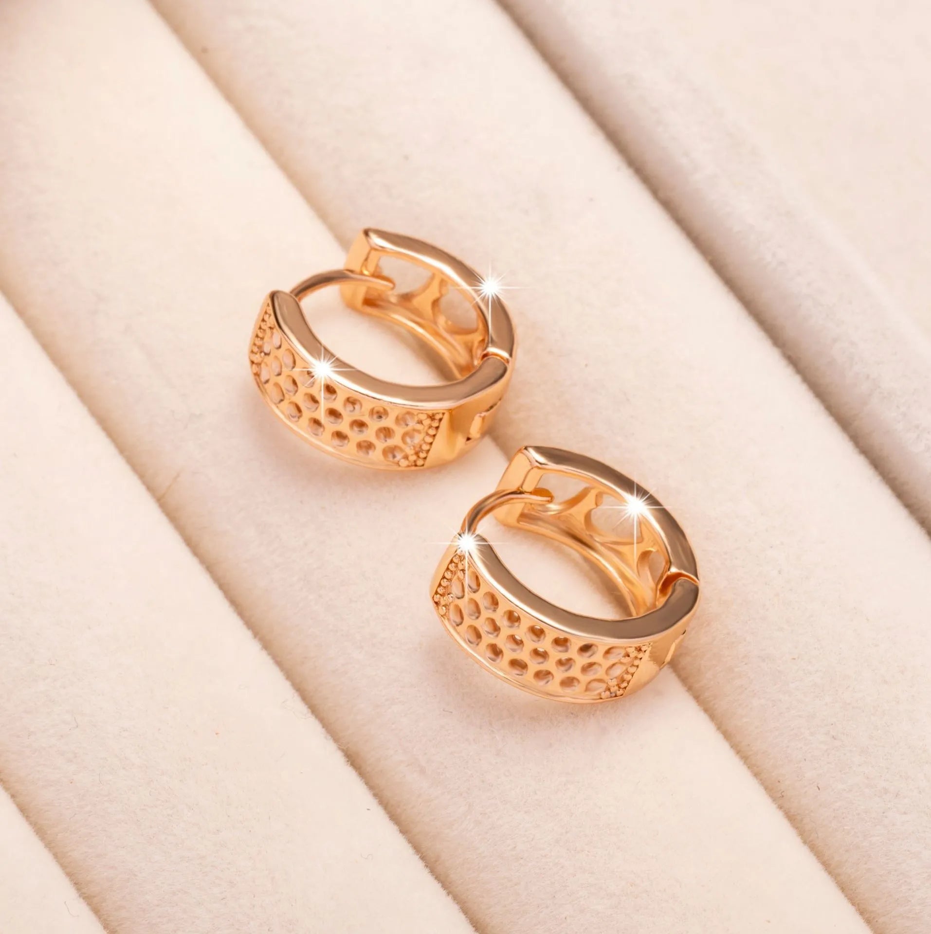 Rose gold hollowed-out heart-shaped earrings with a circular frame on a white background.
