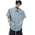 A man's loose-fitting short-sleeved casual shirt in a light colour with a lapel collar and decorative button detail.