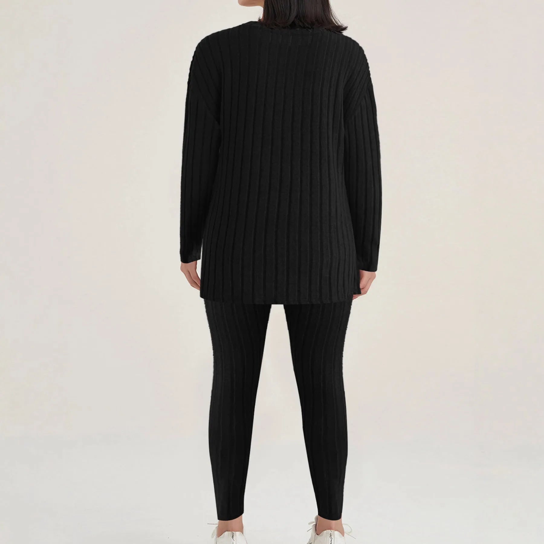 A woman wearing a black sunken stripe two-piece loungewear set, consisting of a regular-sleeve top and elasticated waist trousers.