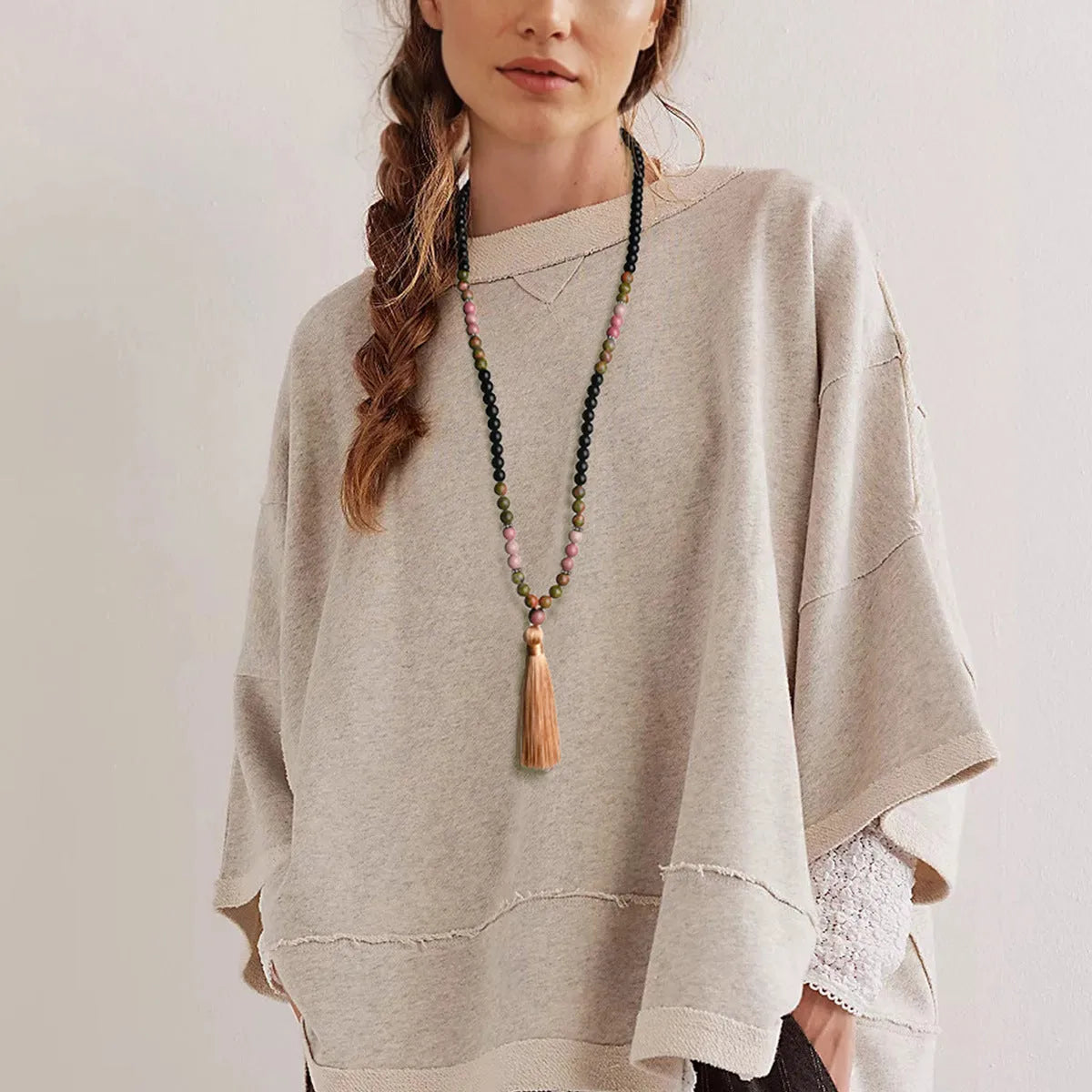 A long bohemian-style necklace with a geometric mixed gemstone pendant and a coloured tassel on a ball bead chain.