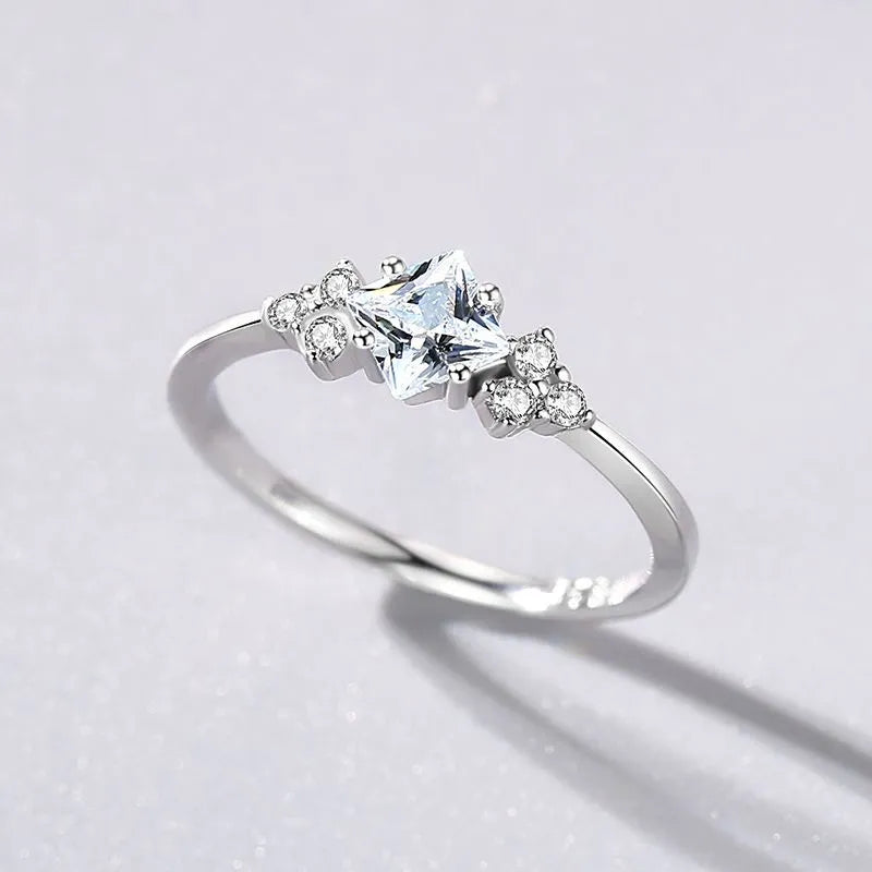 S925 silver ring with rhombus-shaped gold-plated setting and artificial gem on white background