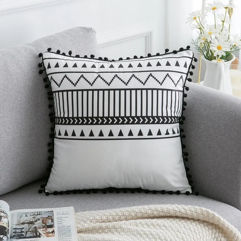 Bohemian style decorative throw pillow with polyester cover in light grey on a sofa.