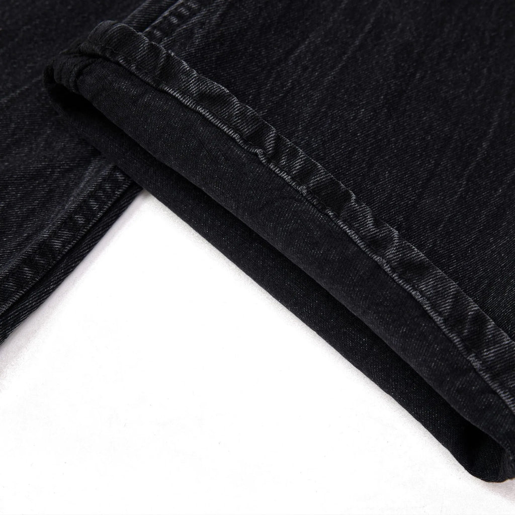 Men's black American washed straight leg jeans with old lightning crack detailing on a plain background