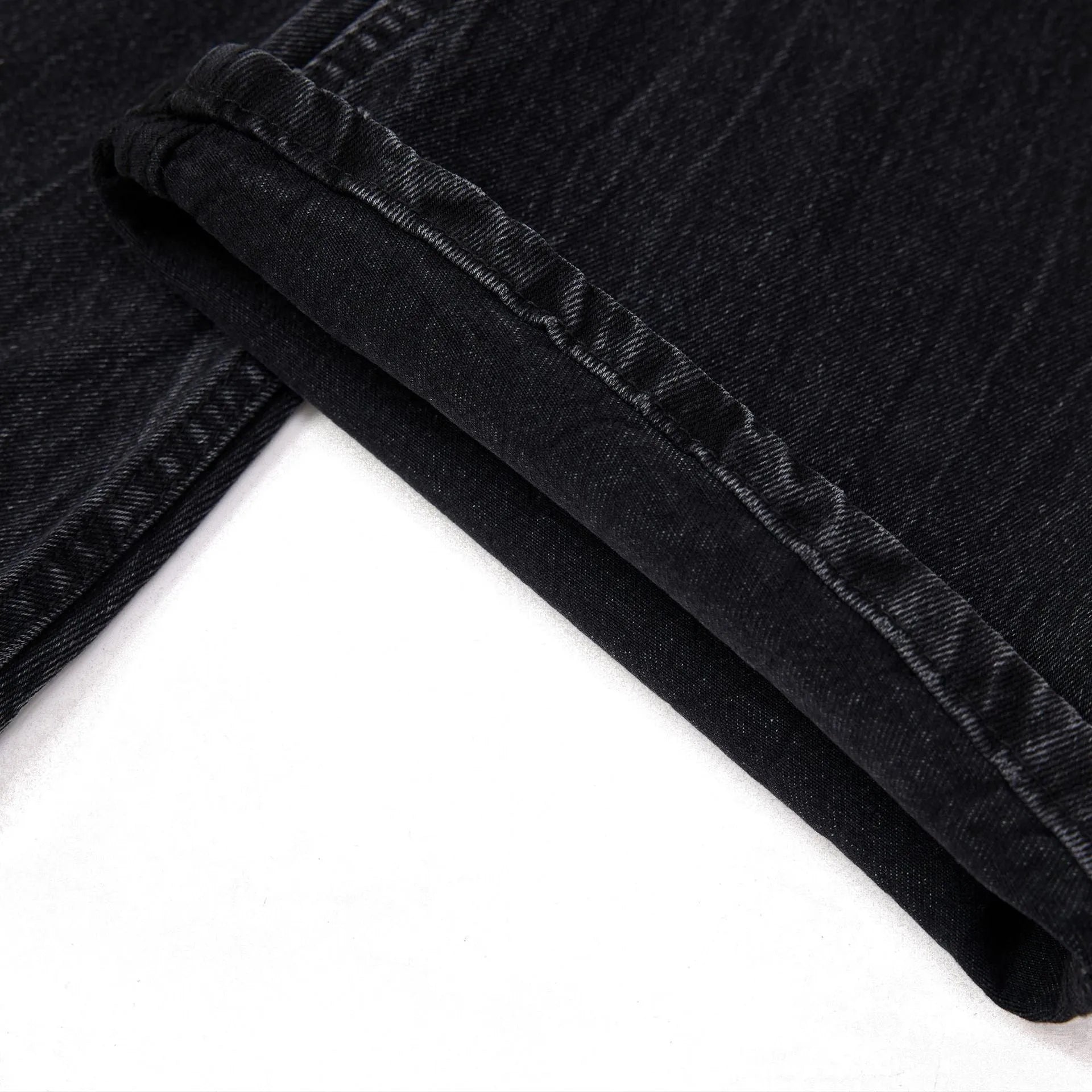 Men's black American washed straight leg jeans with old lightning crack detailing on a plain background