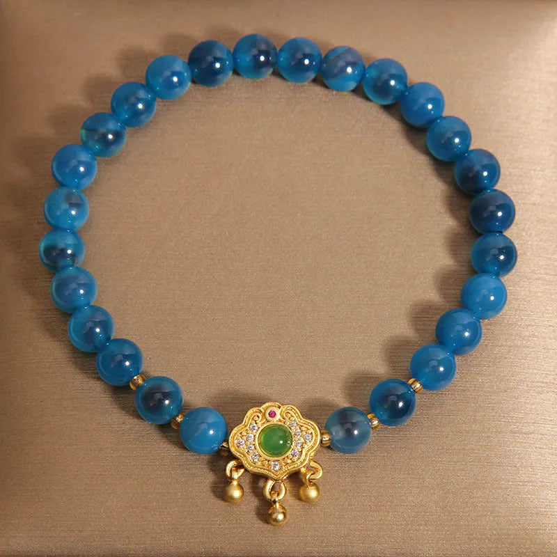 Blue sugar heart agate safety lock pendant on women's bracelet with alloy inlay and crystal accents.