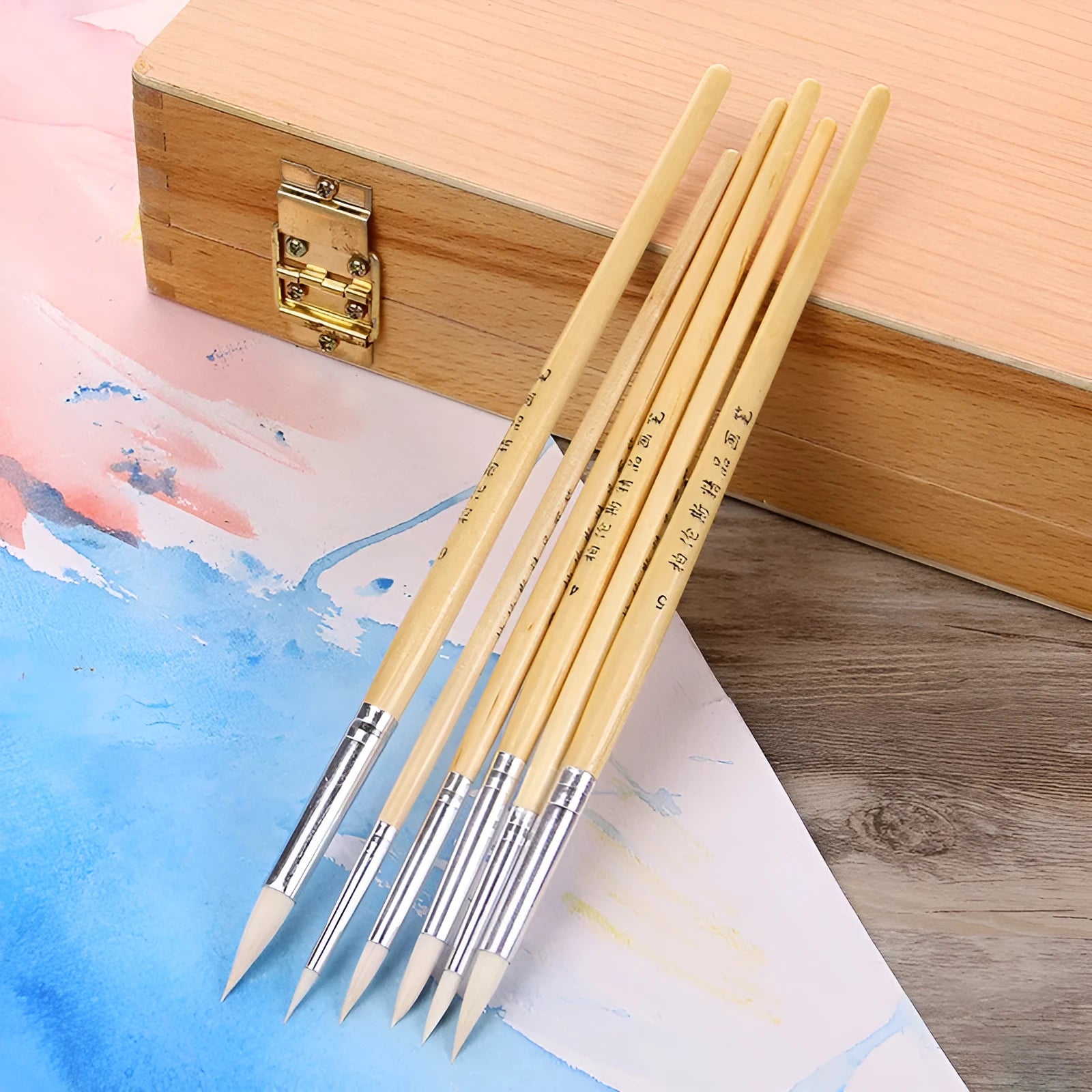 Six wooden hook line pen brushes with pointed handles and fine brush nibs arranged as a set