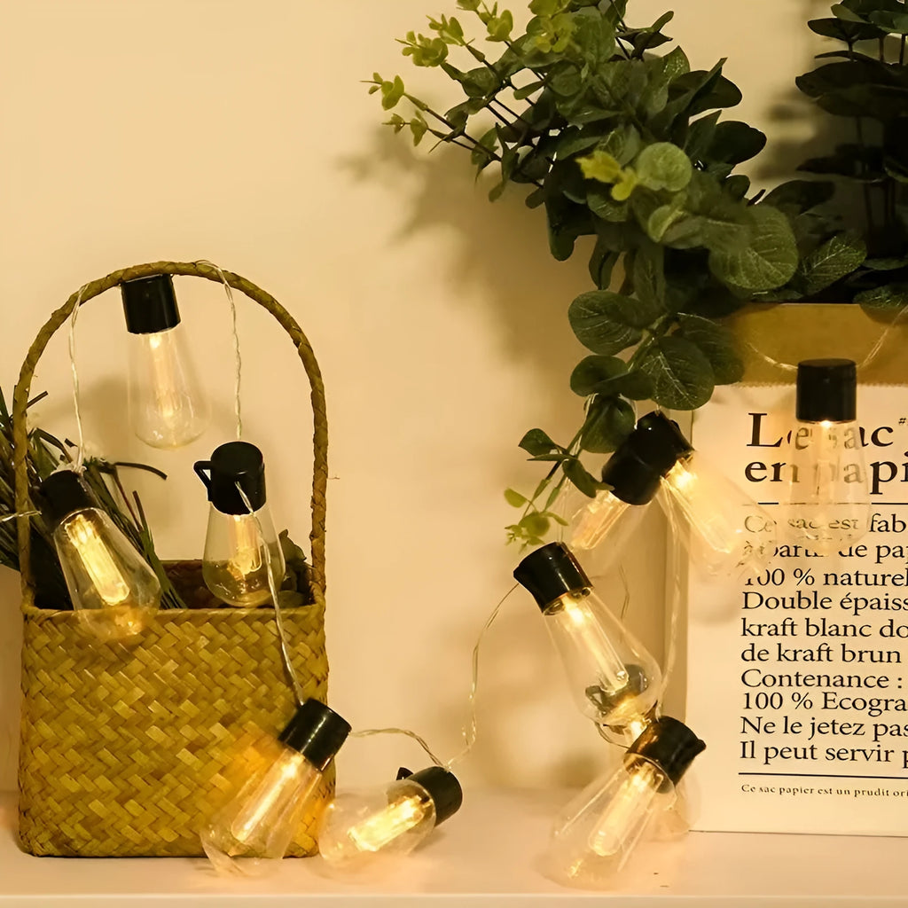 Outdoor retro long bulb infusion bottle shape string lights hanging in a garden setting.