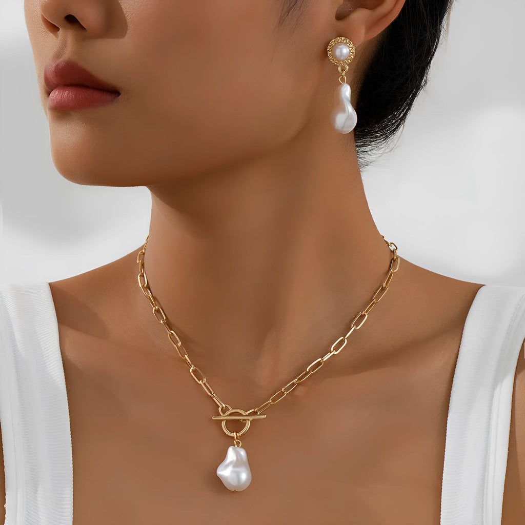Gold-coloured baroque pearl pendant necklace and earring set on a dark background.
