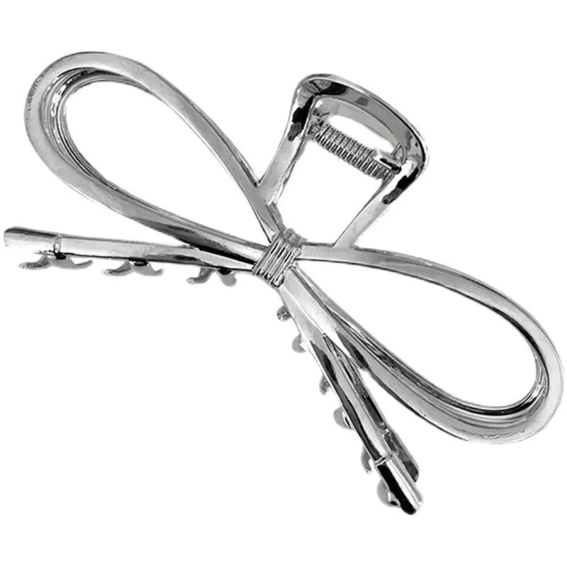 Close-up of a women's gold alloy hair barrette with a bow design and secure clip.