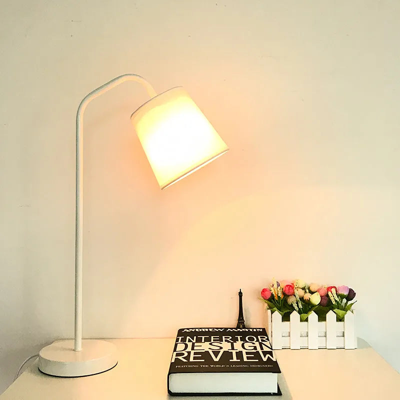 A simple modern Nordic style LED desk lamp with a dimmer switch on a desk.