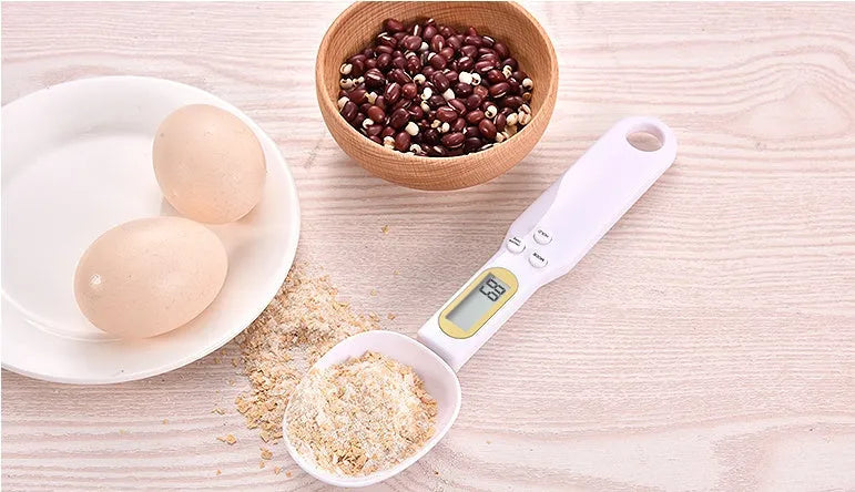 Black electronic digital scale with integrated measuring spoon showing weight display.