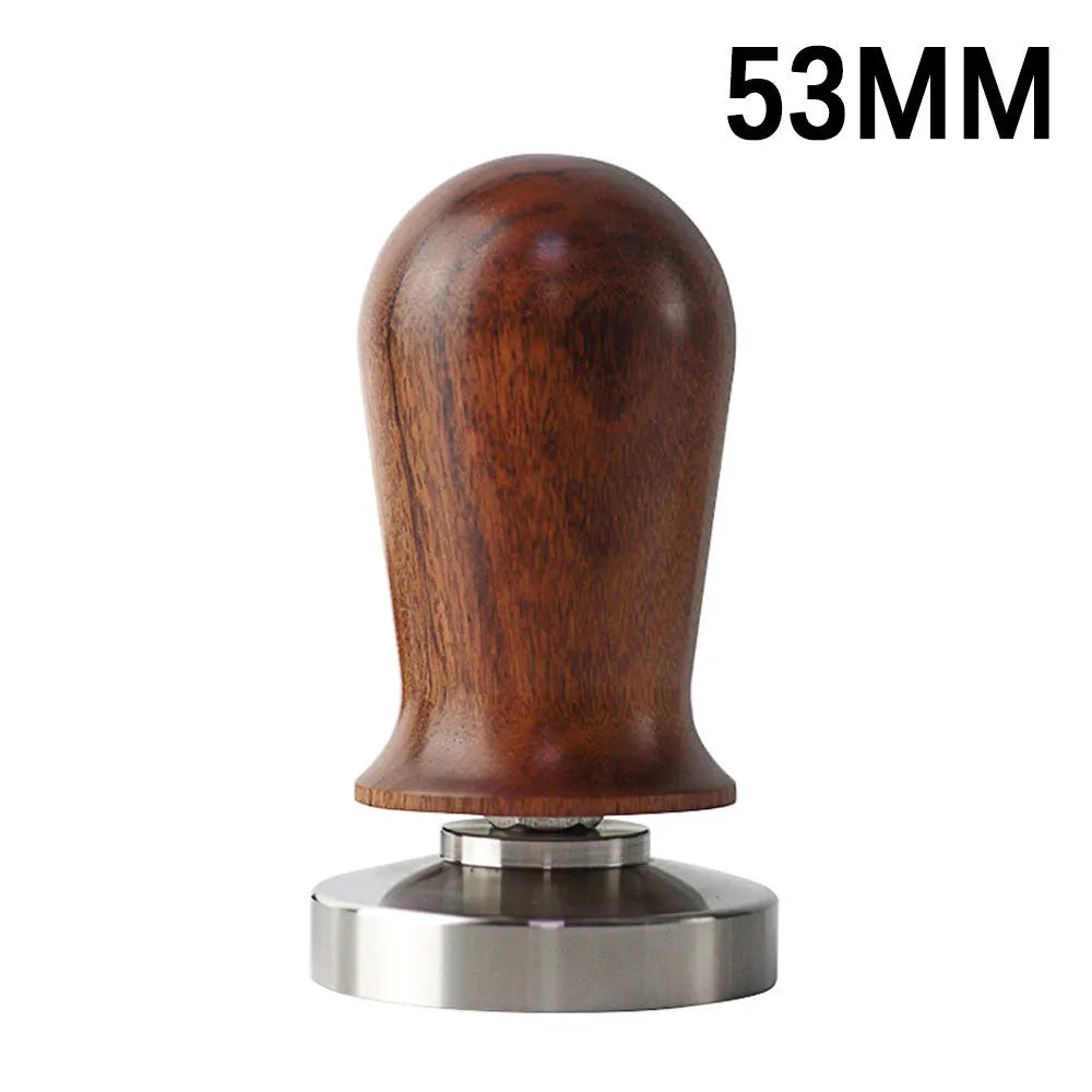 Black and red coffee tamper powder press tool with stainless steel base on a wooden table.
