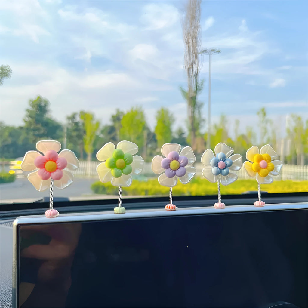 Small colourful plastic swing car decoration on a car dashboard, showing blue, green, pink, purple, and yellow colour options.