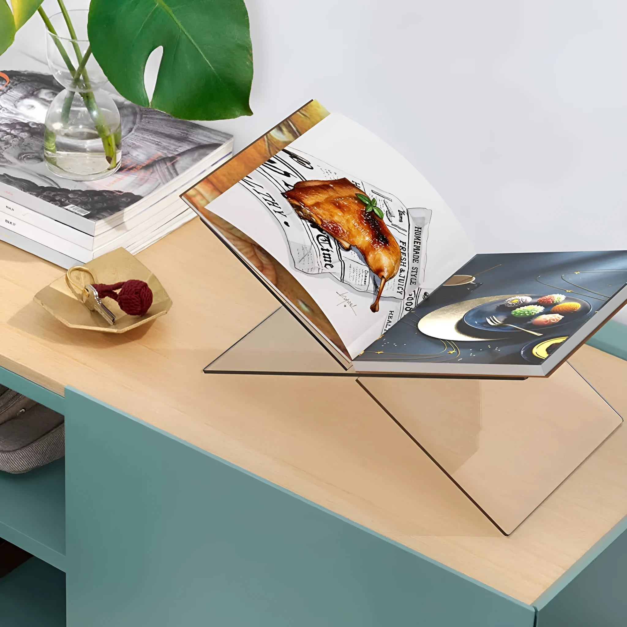 Clear acrylic X-shaped book display rack on desktop with books