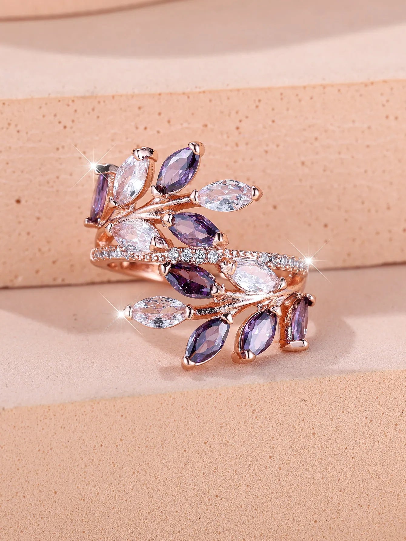 Adjustable copper leaf ring with a central zircon stone on a finger, showing rose gold and platinum colour options.