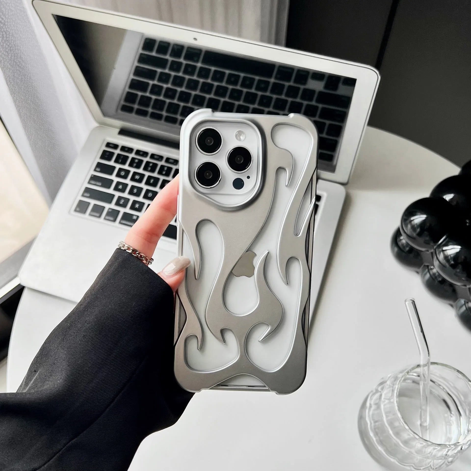 Silver electroplated iPhone case with hollow flame pattern design on a dark background