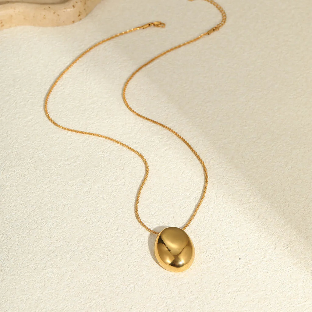 Gold geometric pendant necklace with adjustable chain on plain background