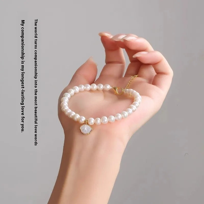 A women's freshwater pearl bracelet with a fan-shaped shell clasp, shown in both elastic and extension chain fastening styles.