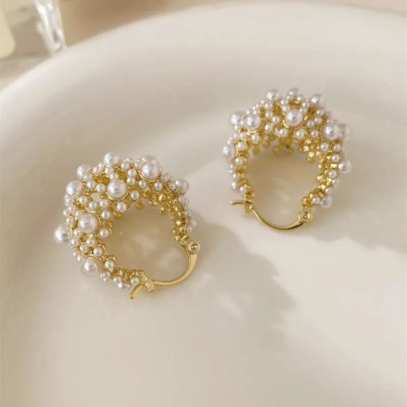 A pair of gold-coloured copper flower basket earrings with pearl inlay and small rice-shaped bead details.