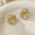 A pair of gold-coloured copper flower basket earrings with pearl inlay and small rice-shaped bead details.