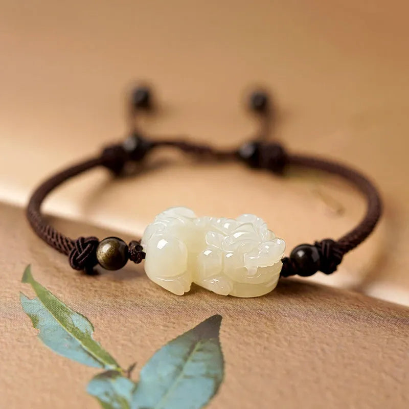 Close-up of a brown and black braided rope bracelet with a central Hetian jade bead on a wrist.