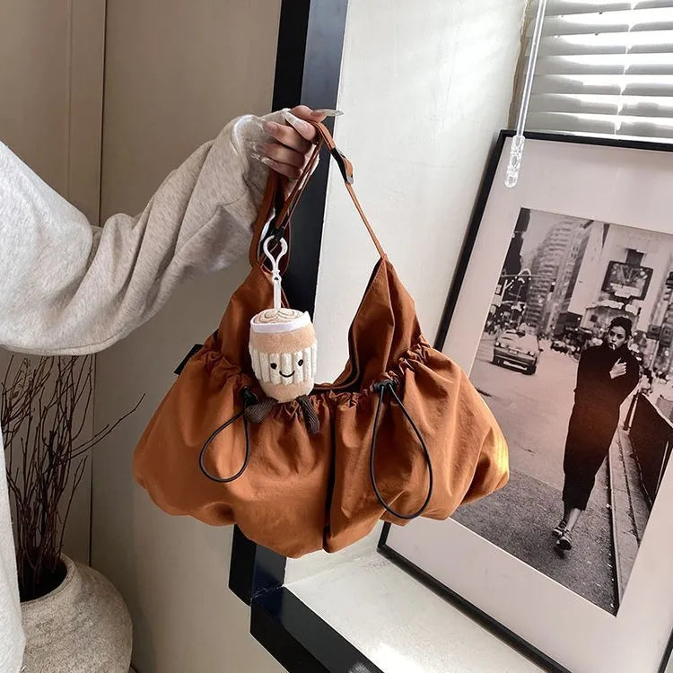 Ultra-light foldable pleated crossbody bag in polyester showing split pockets and mobile phone compartment.
