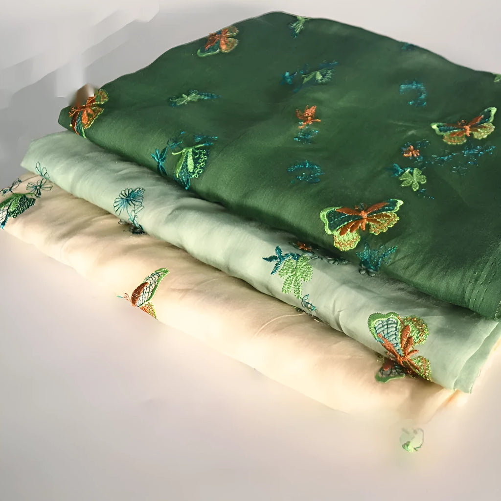Roll of beige, grass green, and dark green 100% ramie fabric showing its texture and 140cm width.