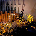 Iron solar garden lamp with tapered butterfly pattern and warm white LED light.