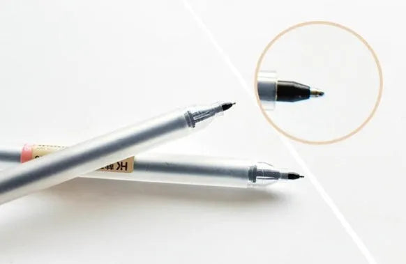 Set of twelve black Muji retractable gel pens with 0.5mm tips, laid out on a notepad.