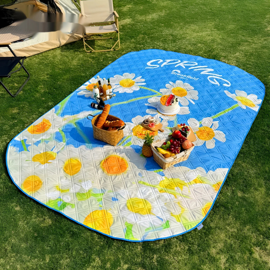 Large green waterproof picnic mat unrolled on grass, showing its textured surface and size.