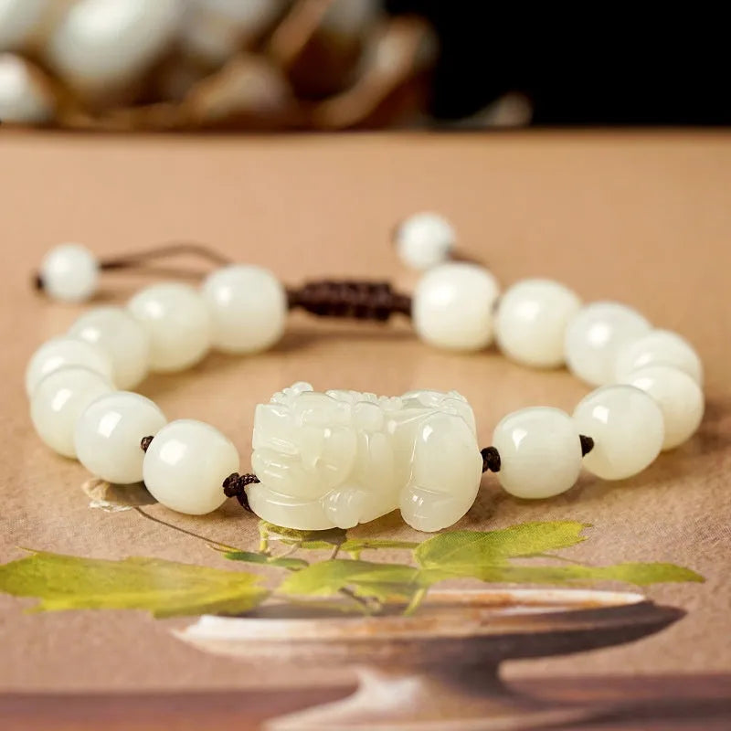 Close-up of a brown and black braided rope bracelet with a central Hetian jade bead on a wrist.