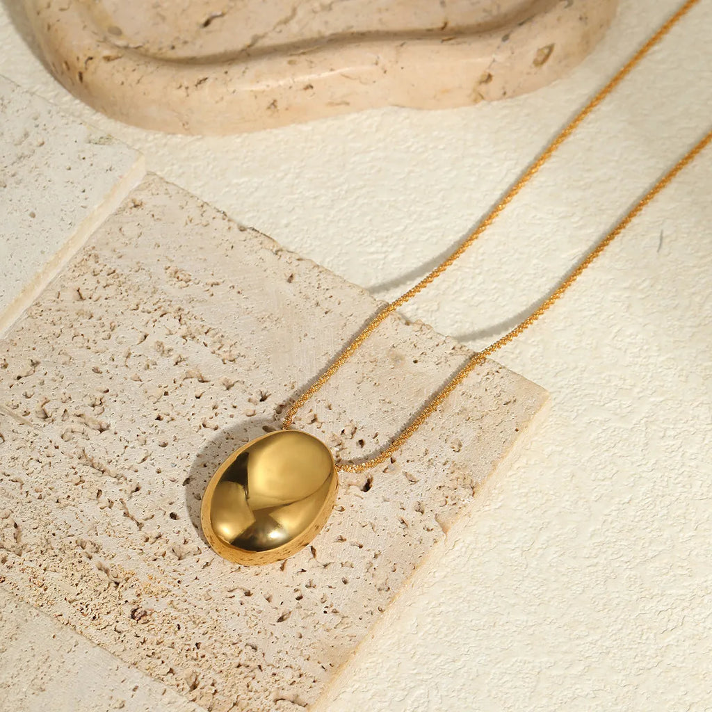 Gold geometric pendant necklace with adjustable chain on plain background