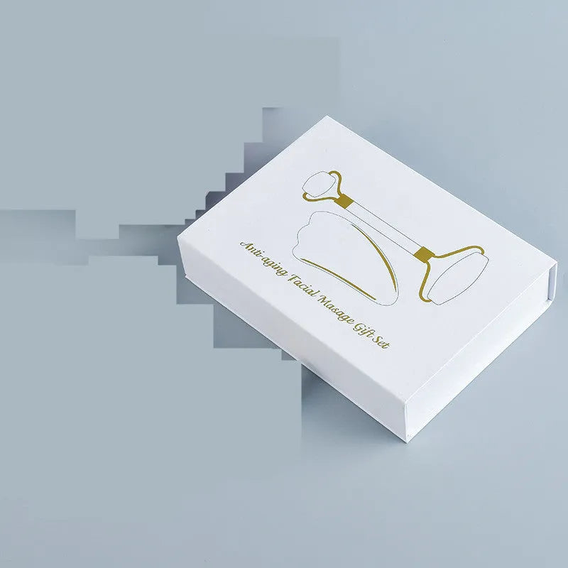 White jade facial roller and Gua Sha scraping board set on a neutral background.