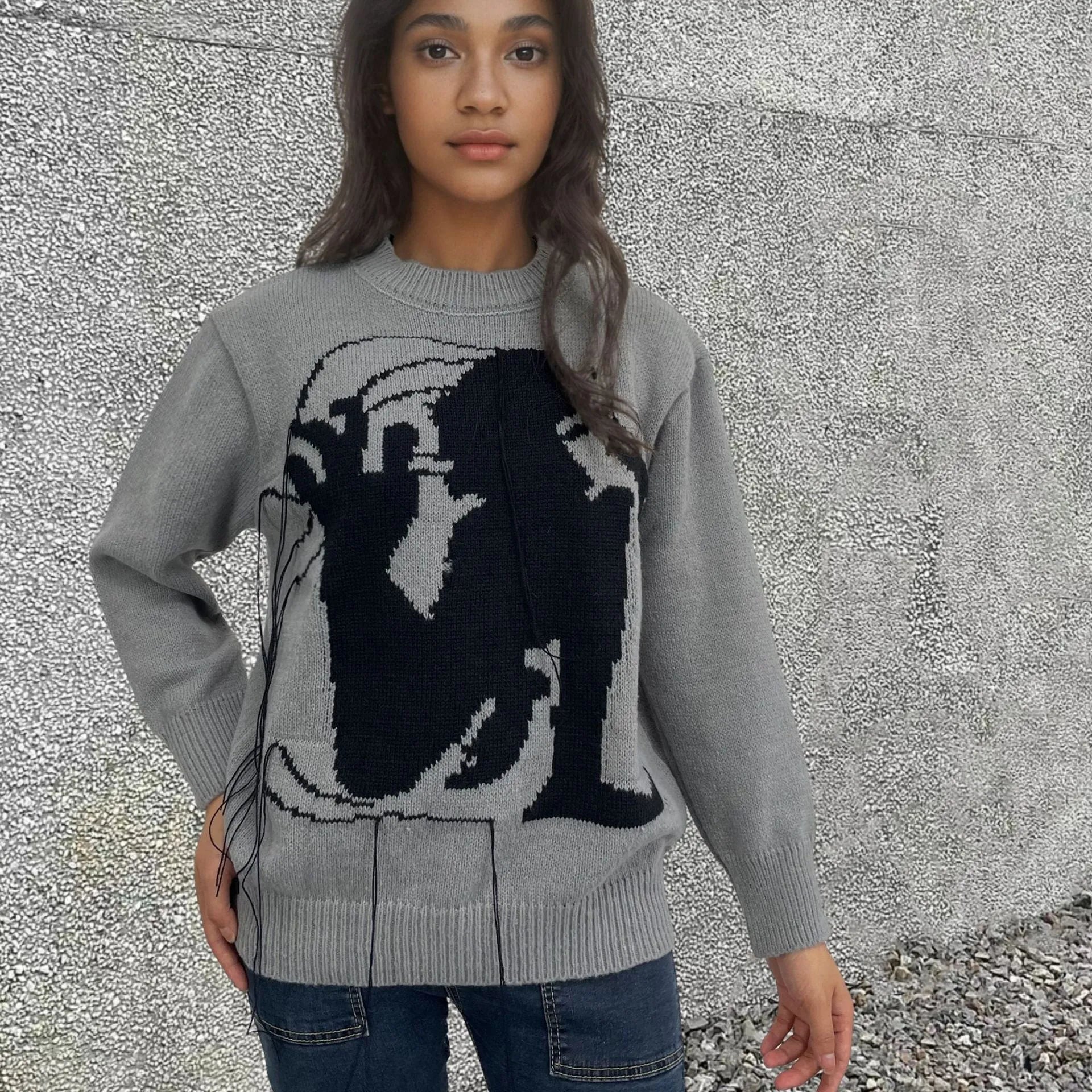 Grey women's alpaca wool sweater with abstract pattern and tassel detailing on a hanger.