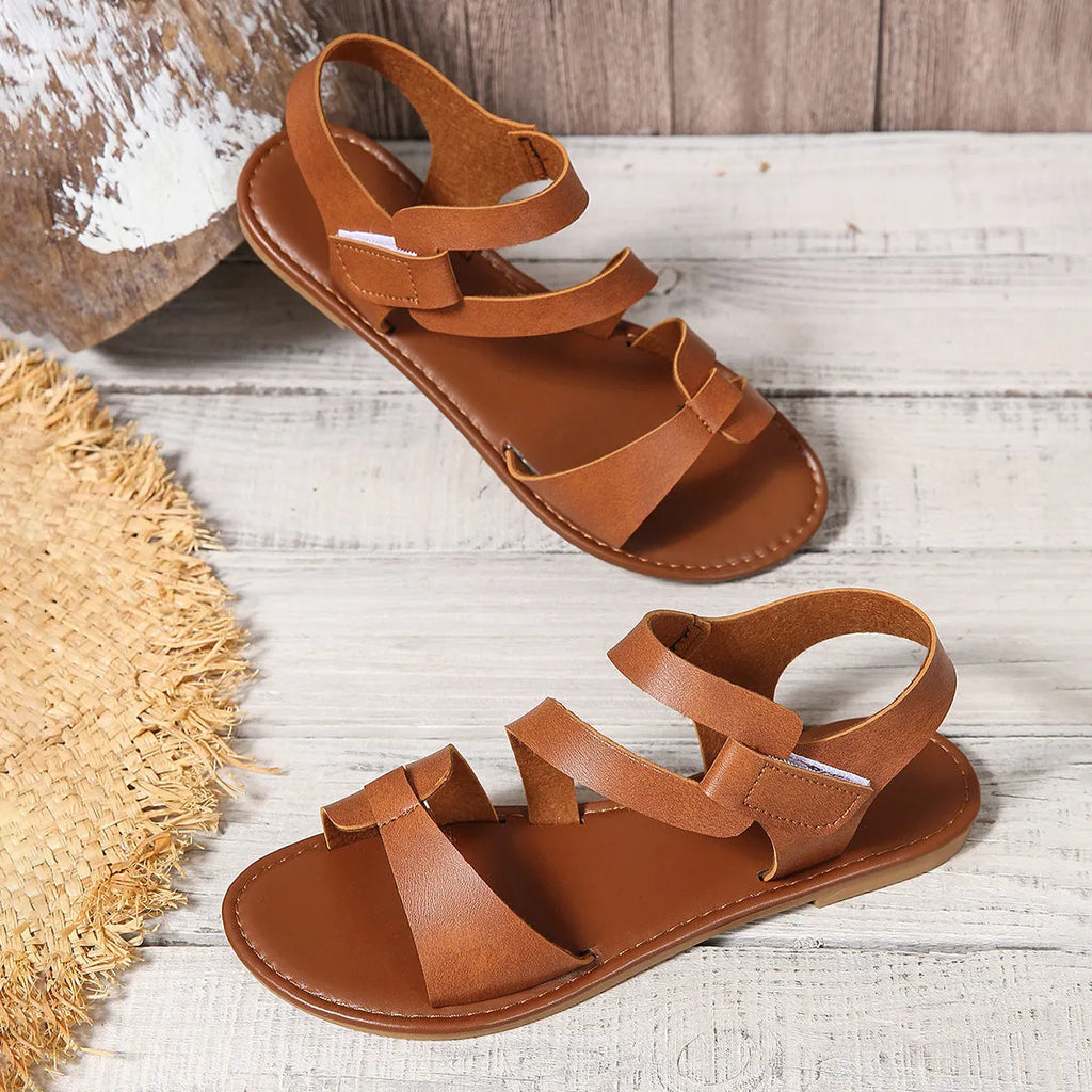 Women's flat sandals with Velcro strap, round toe, and rubber sole in black, brown, and colourful options.