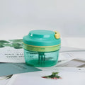 Green manual hand-pulled food grinder with transparent container and stainless steel blade for baby food and herbs.