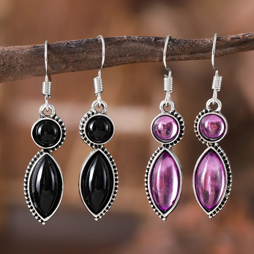 Close-up of vintage black and purple geometric drop earrings with a circular pendant on a long chain.