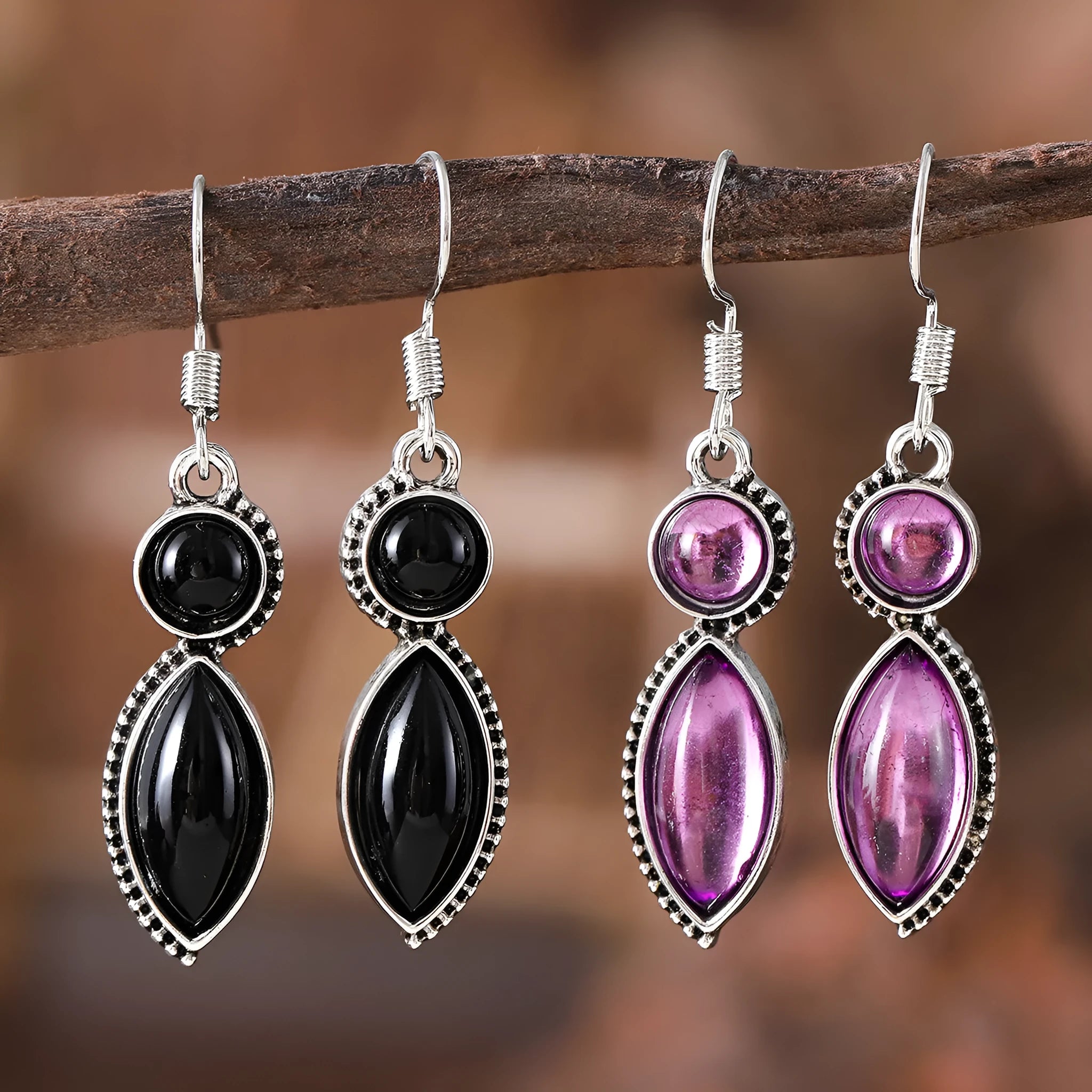 Close-up of vintage black and purple geometric drop earrings with a circular pendant on a long chain.