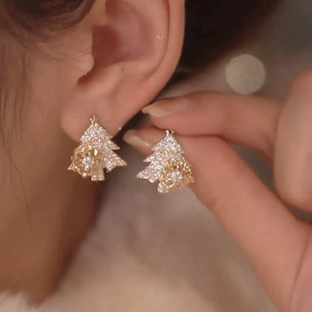 Pair of rotatable Christmas tree stud earrings with rhinestone snowflake detail in gold on a white background