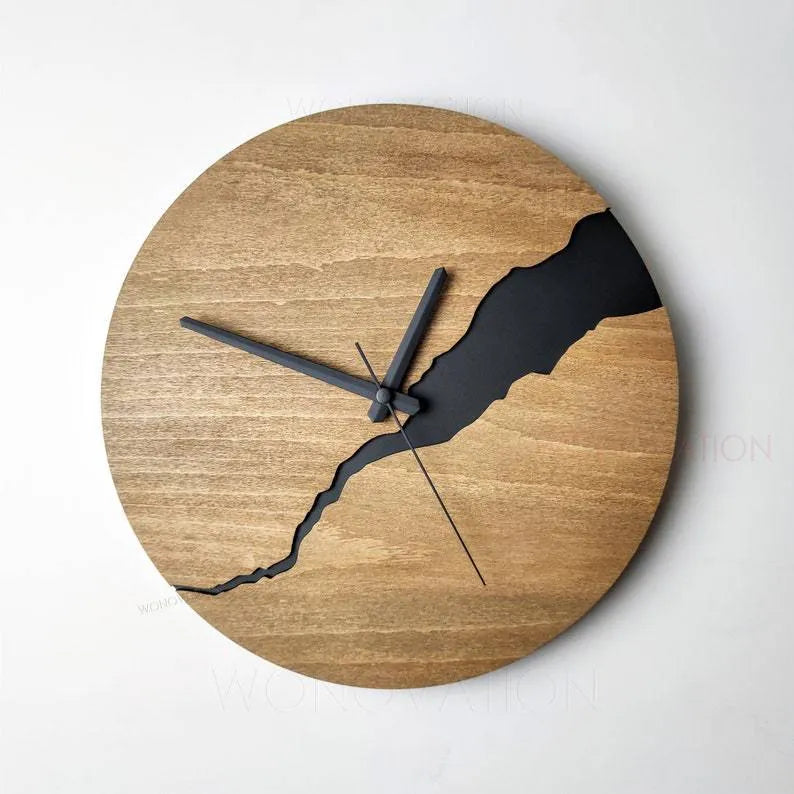 Modern simple wooden wall clock with a crack design dial on a light wood background.