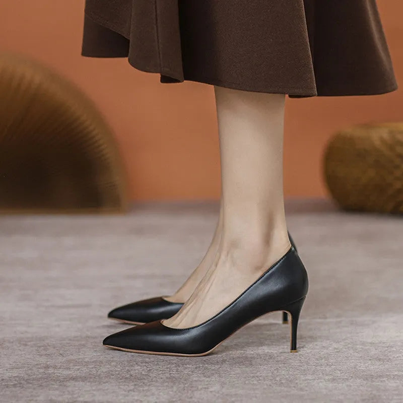 Black pointed-toe high heel pump with a stiletto heel on a plain background.