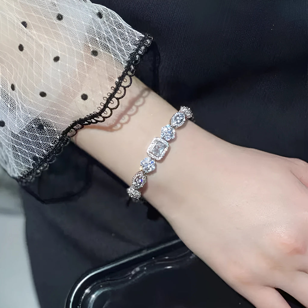Women's geometric silver bracelet with inlaid zircon stones on a wrist, showing adjustable chain.