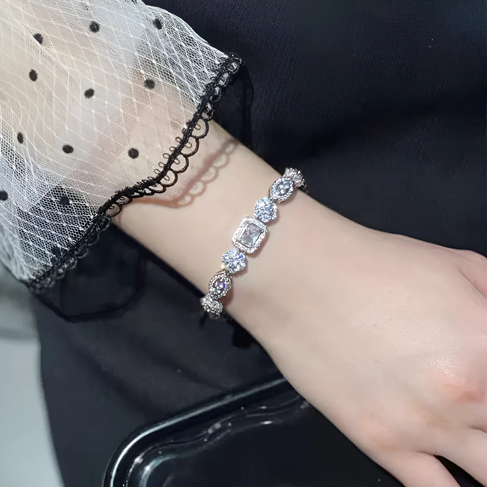 Women's geometric silver bracelet with inlaid zircon stones on a wrist, showing adjustable chain.